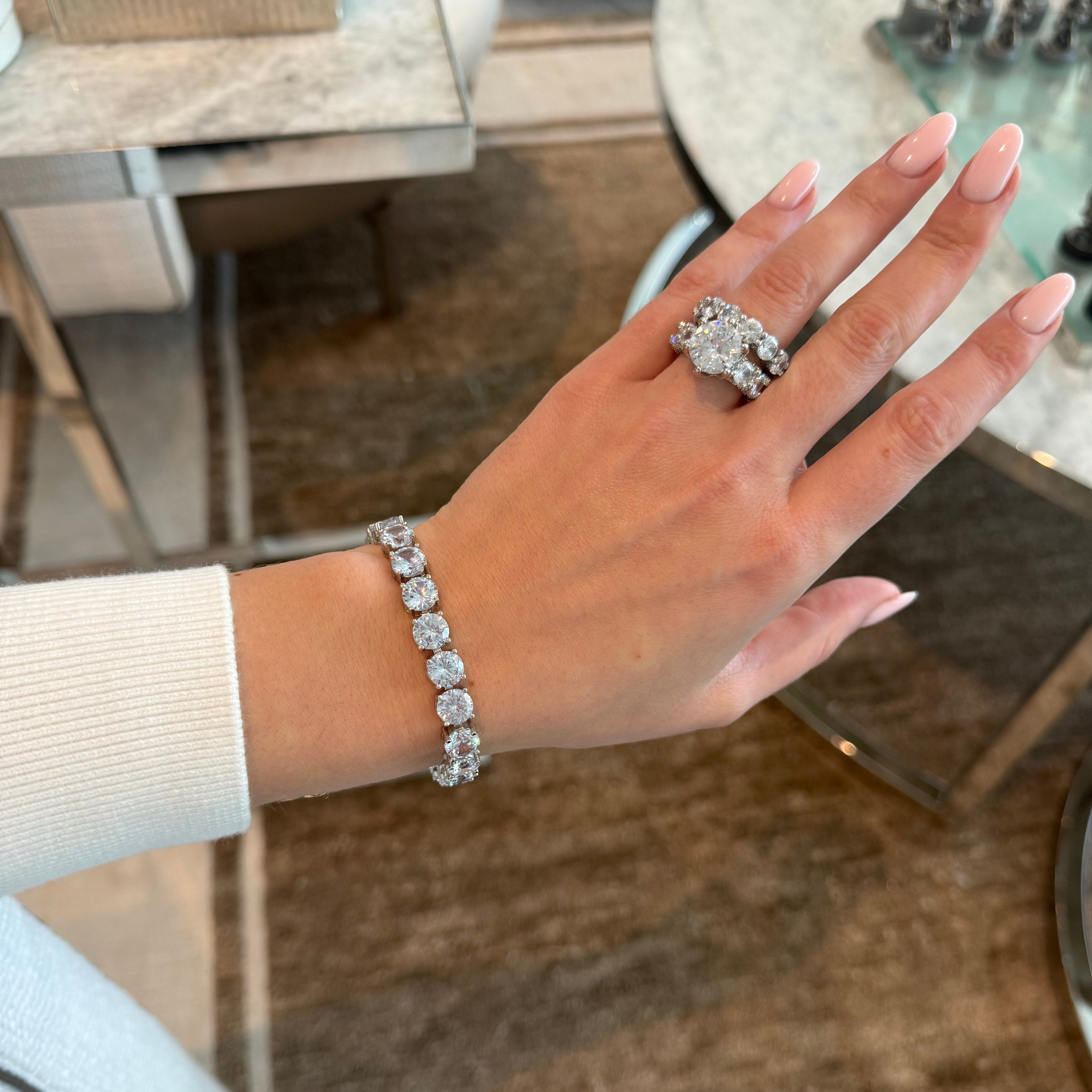 Hand wearing a diamond ring and bracelet with a blurred background