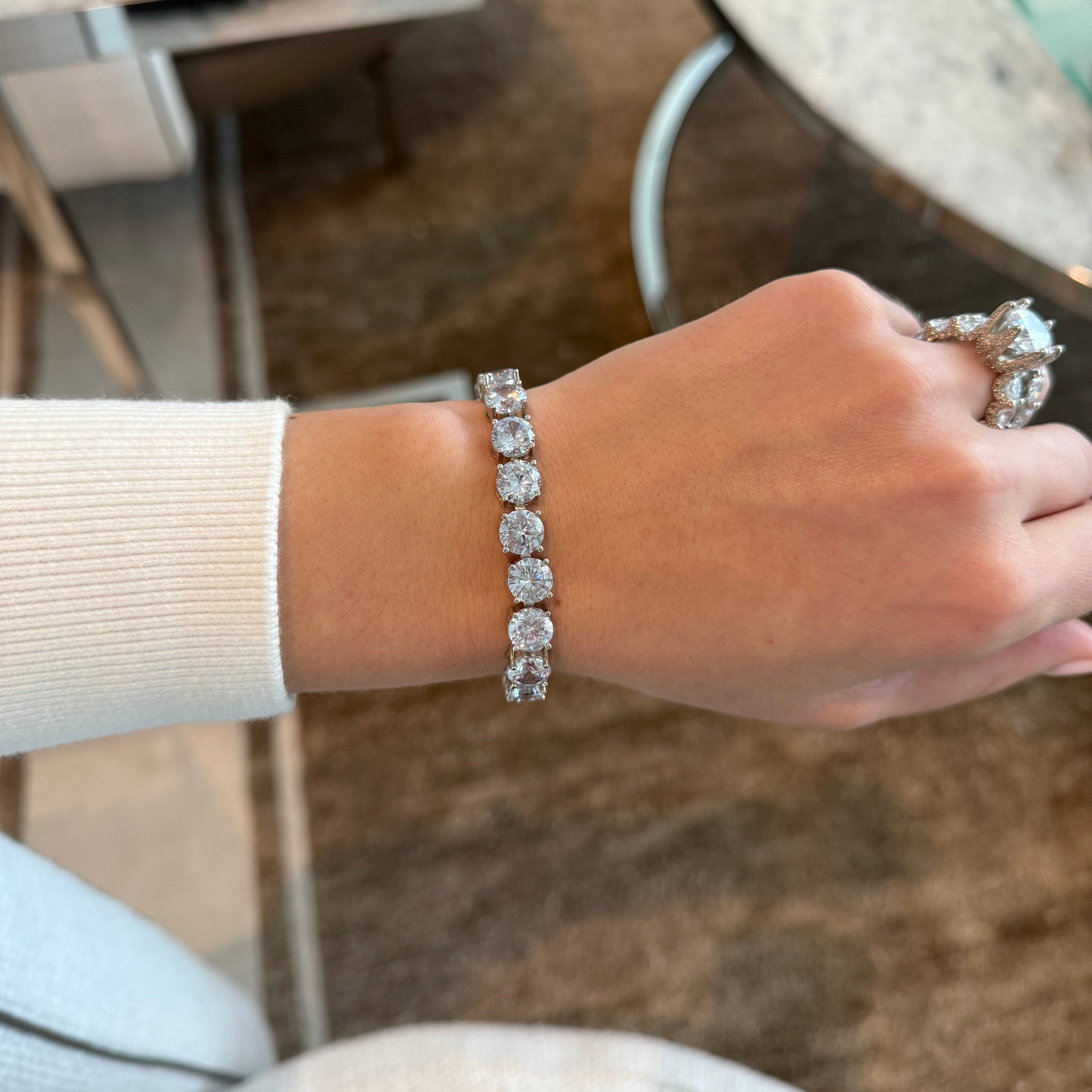 Hand wearing a silver bracelet with a blurred background