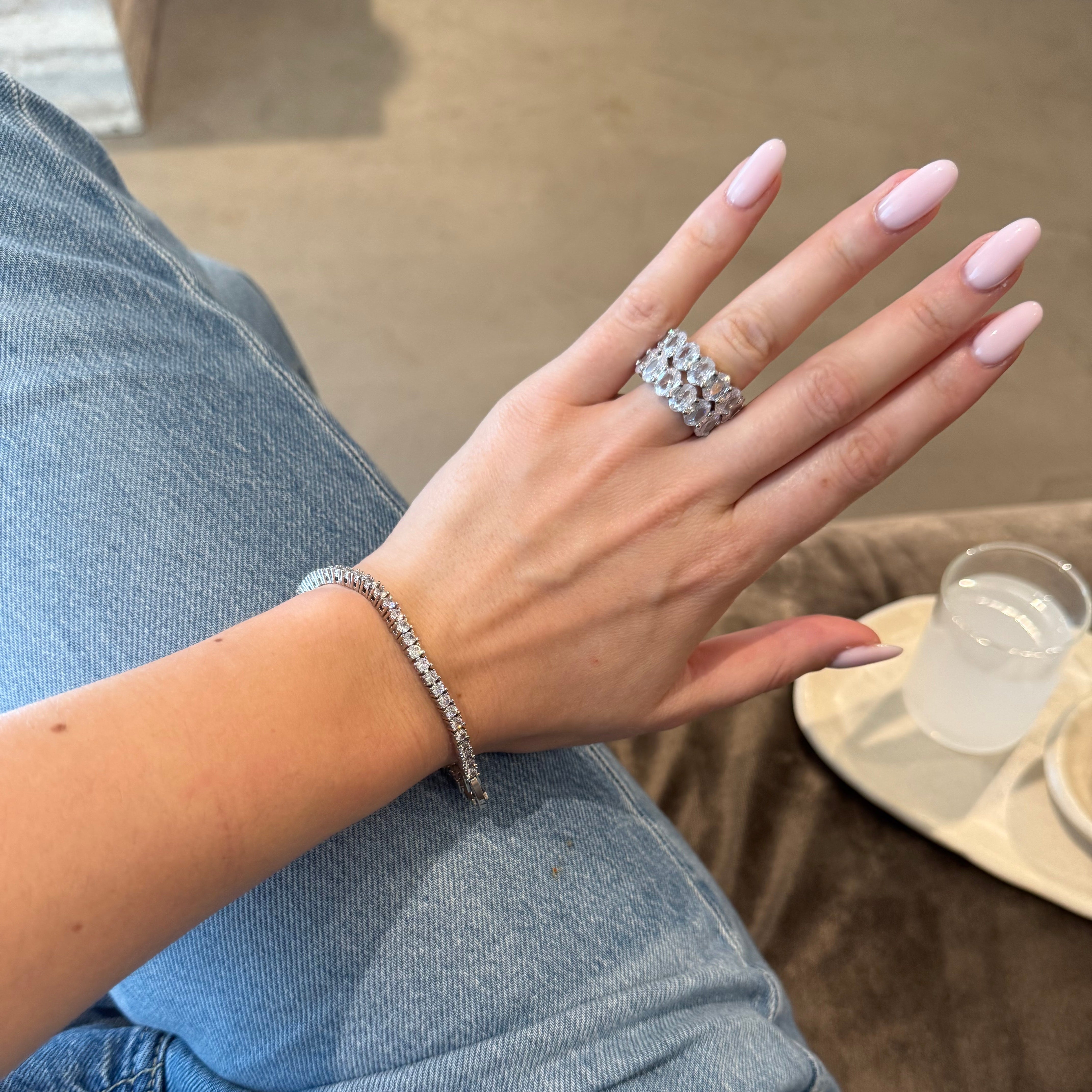 Hand wearing two diamond rings and bracelet with a blurred background