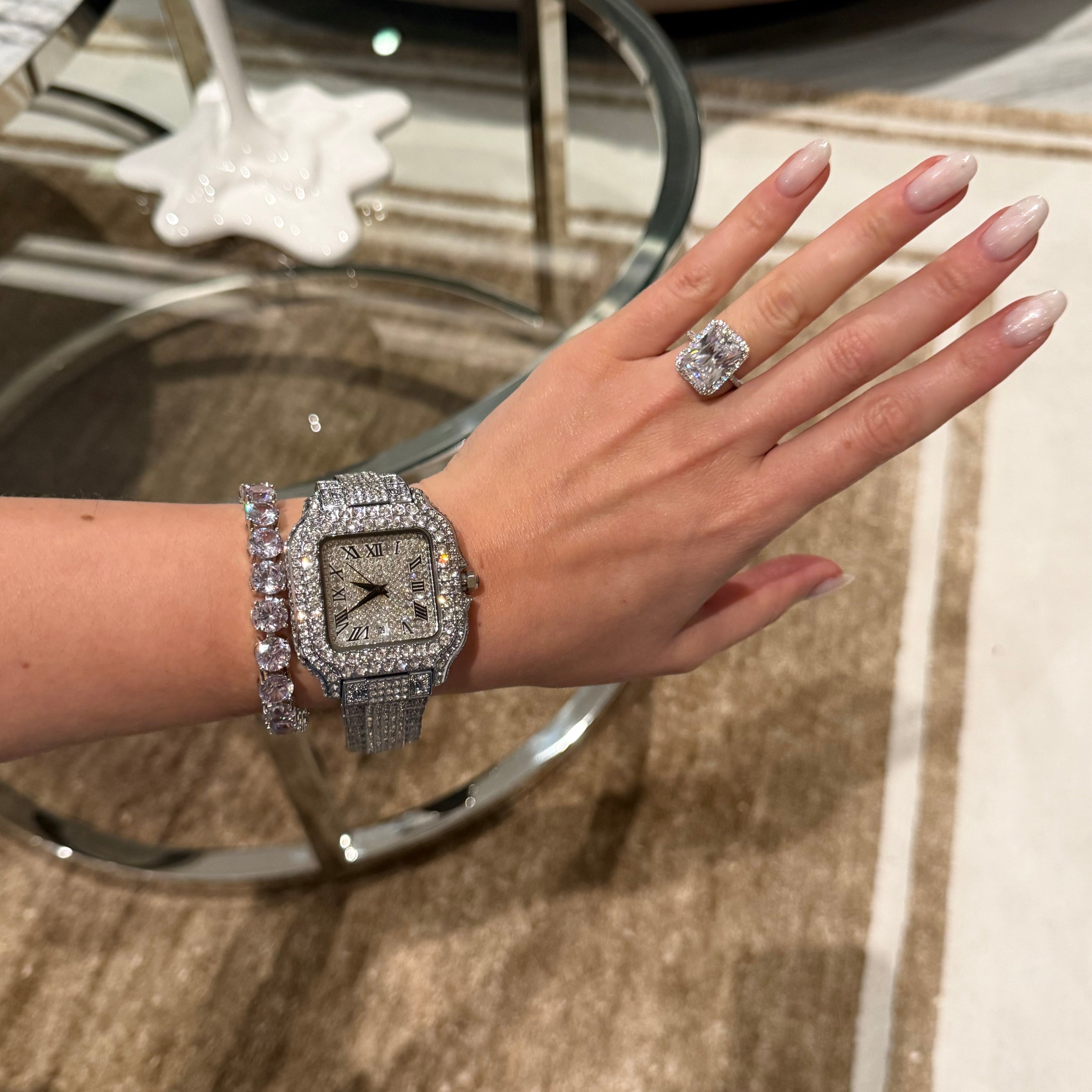 Hand wearing a diamond ring and watch with a blurred background