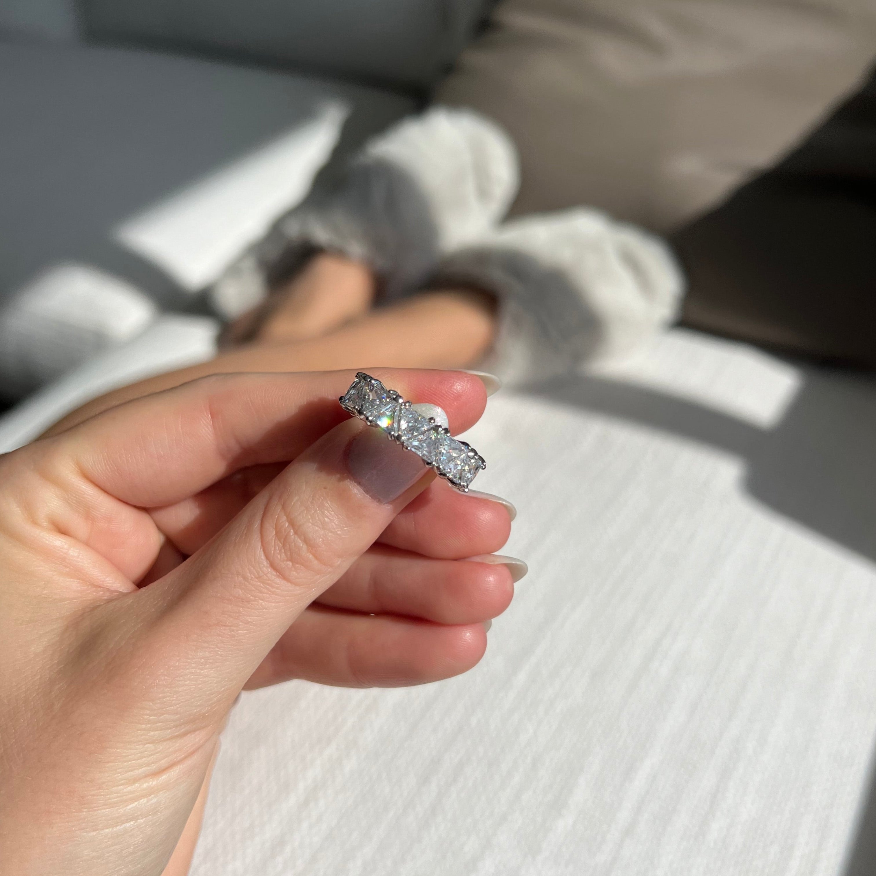Hand holding a diamond ring with a blurred background