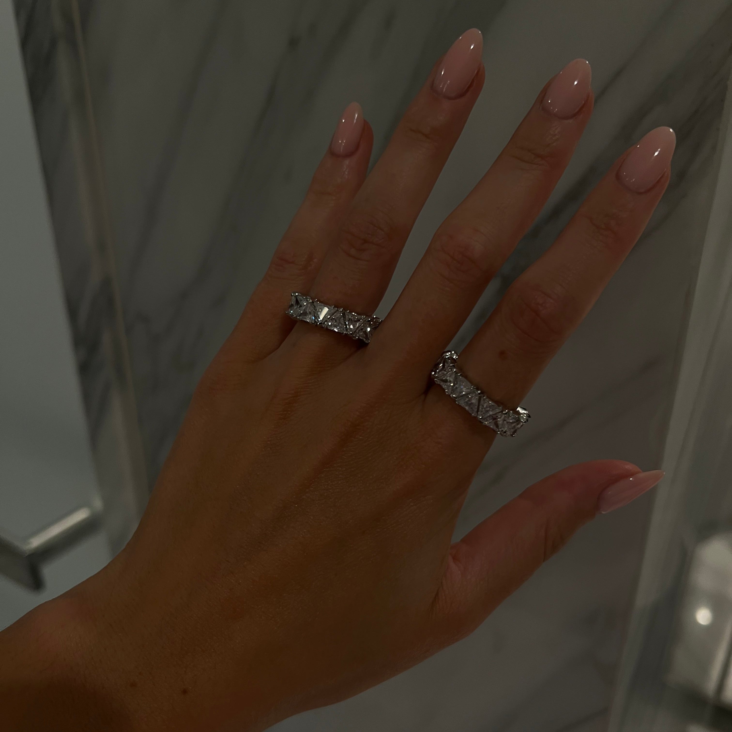Hand wearing two diamond rings with a blurred background