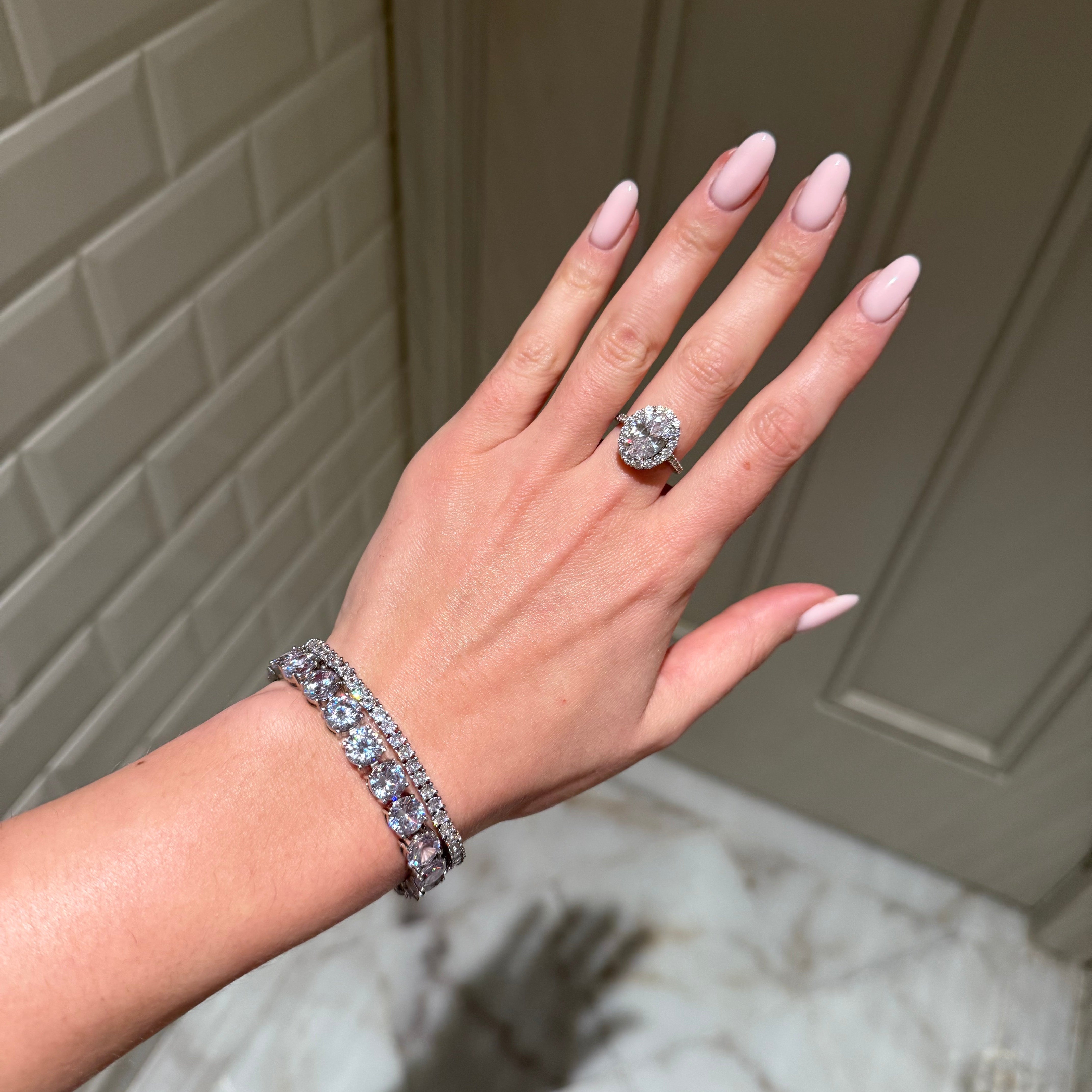 Hand wearing a ring and bracelet with a neutral background