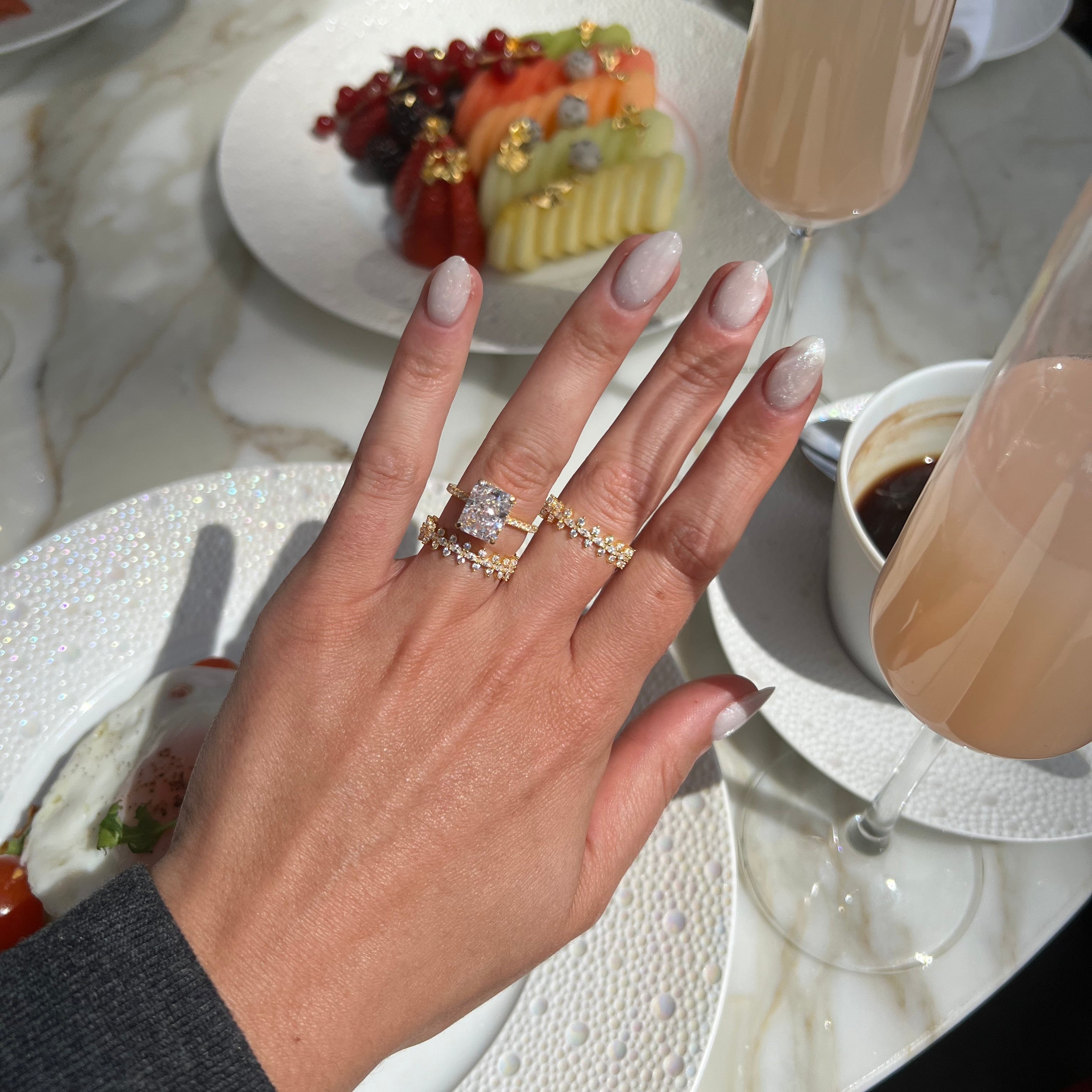 Hand with a ring, a dessert plate with a glass of white wine on a table.